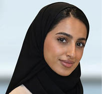 مبنى حديث بتصميم معماري معاصر محاط بأشجار ونباتات خضراء وزهور برتقالية في المقدمة. Description generated by AI