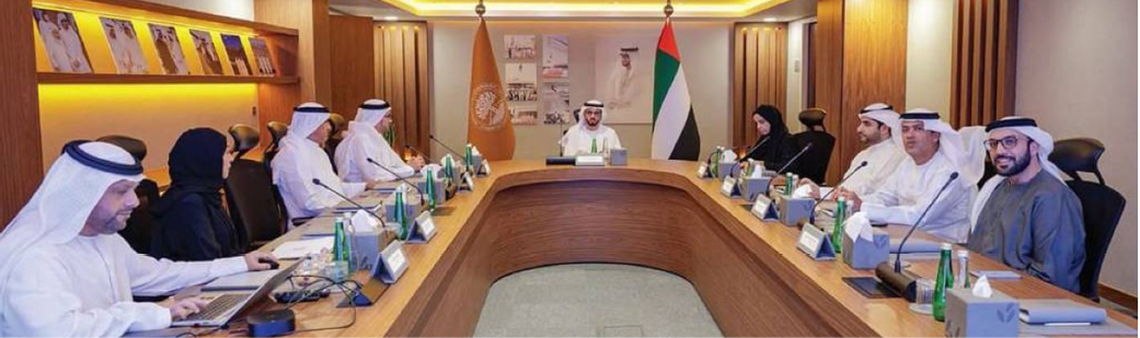 مبنى كبير ذو طراز معماري كلاسيكي مع قبة في الأعلى يحيط به أشجار النخيل ونافورة مياه في المقدمة تحت سماء زرقاء مع بعض الغيوم. Description generated by AI