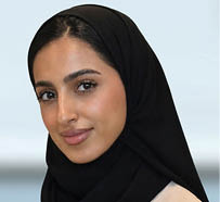 مبنى حديث بتصميم معماري معاصر محاط بأشجار ونباتات خضراء وزهور برتقالية في المقدمة. Description generated by AI
