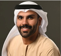 مبنى حديث بتصميم معماري معاصر محاط بأشجار ونباتات خضراء وزهور برتقالية في المقدمة. Description generated by AI