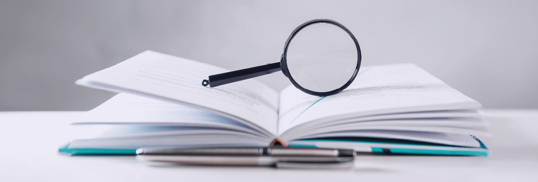 Magnifying lens over open paper book with pages. Concept of academic research.