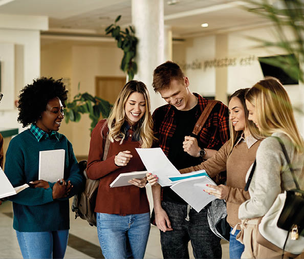 Happy female student showing test results to her friends while standing in a lobby. 