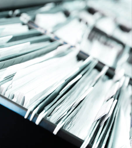 Multiple rows of filing cabinets in an office or medical establishment, overflowing with files. Narrow depth of field to emphasize the “neverending" feeling